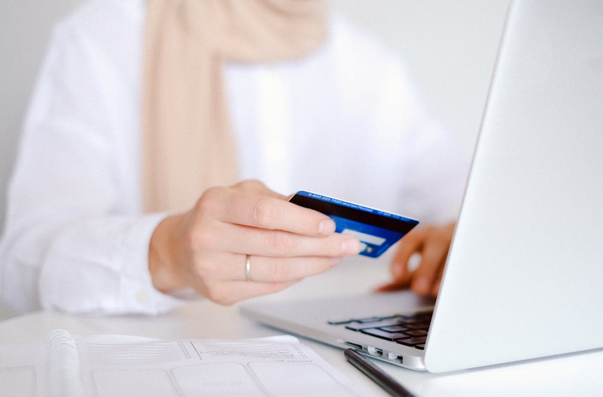 Person holding credit card while entering payment on laptop